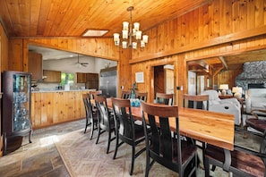 A wooden interior with a dining area, kitchen, and a stone fireplace. - Eagle's Landing | Cozy, Pet-Friendly Getaway (Hammondsport)