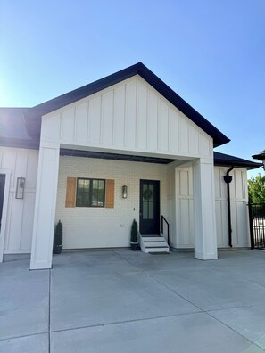 A modern house with a white exterior, a black door, and a small front porch.