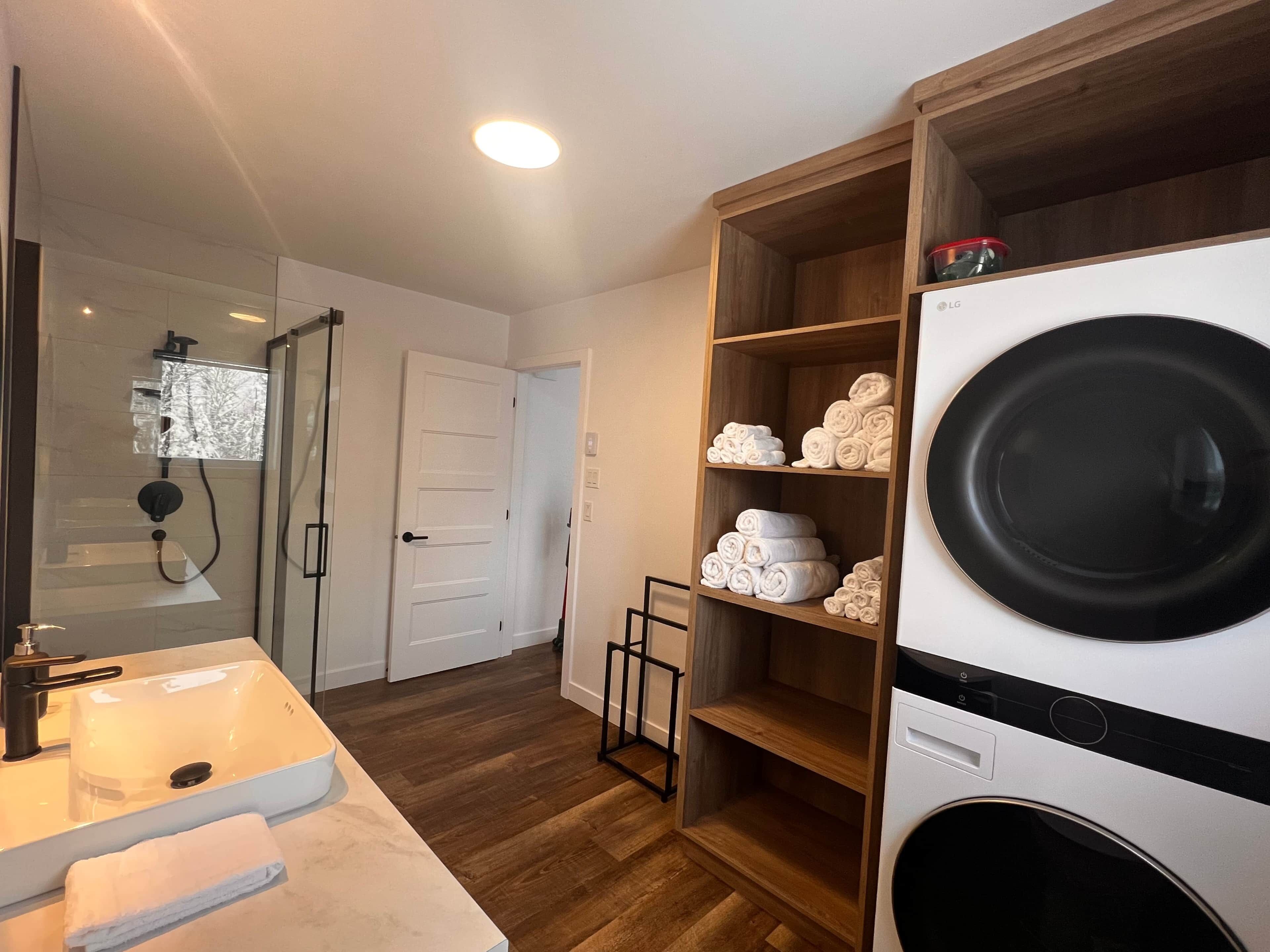 Une salle de bain moderne équipée d’un lavabo, d’un miroir et d’un lave-linge encastré.