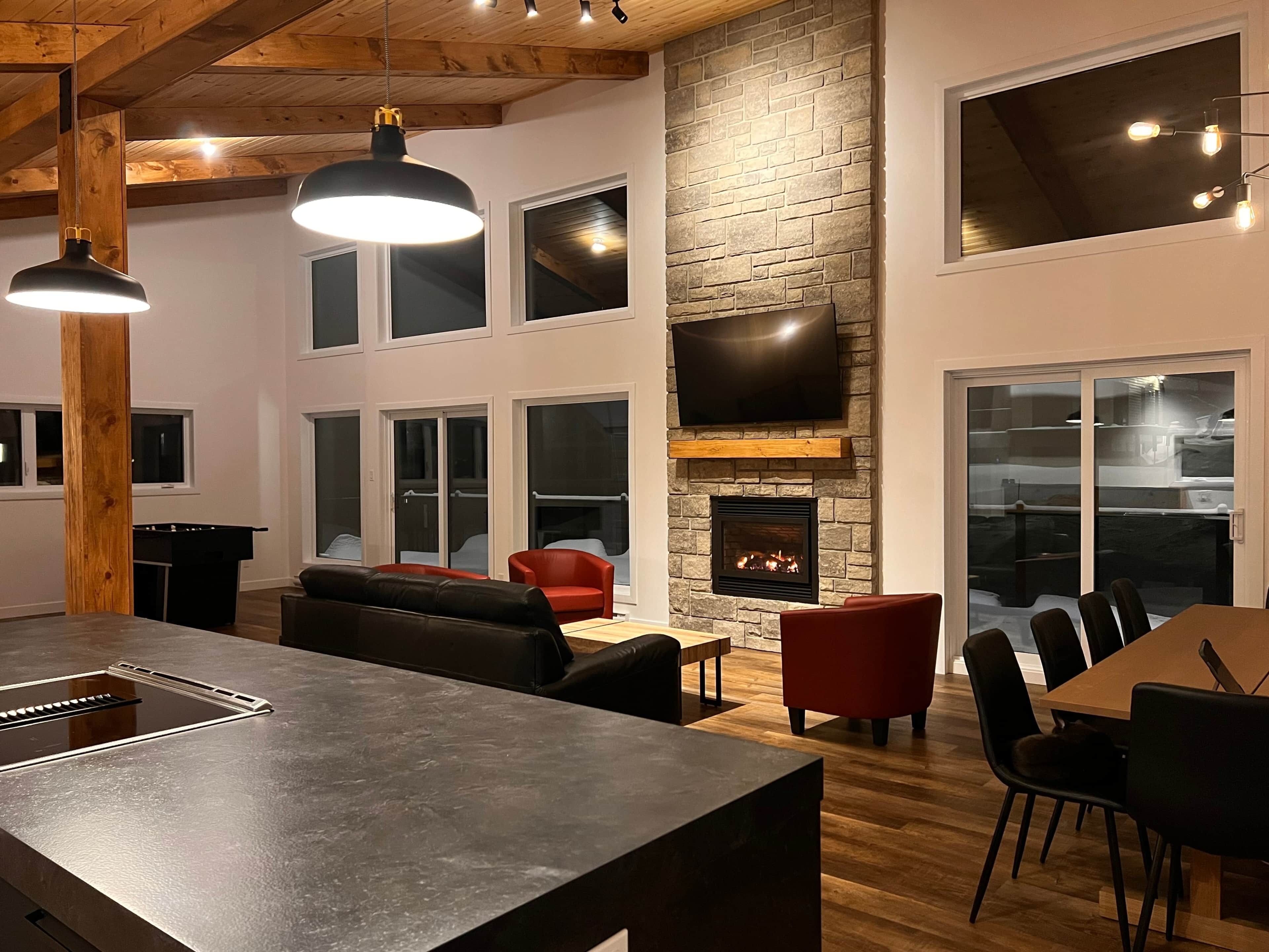 A modern living room with a fireplace, a flat-screen TV, and a dining area.