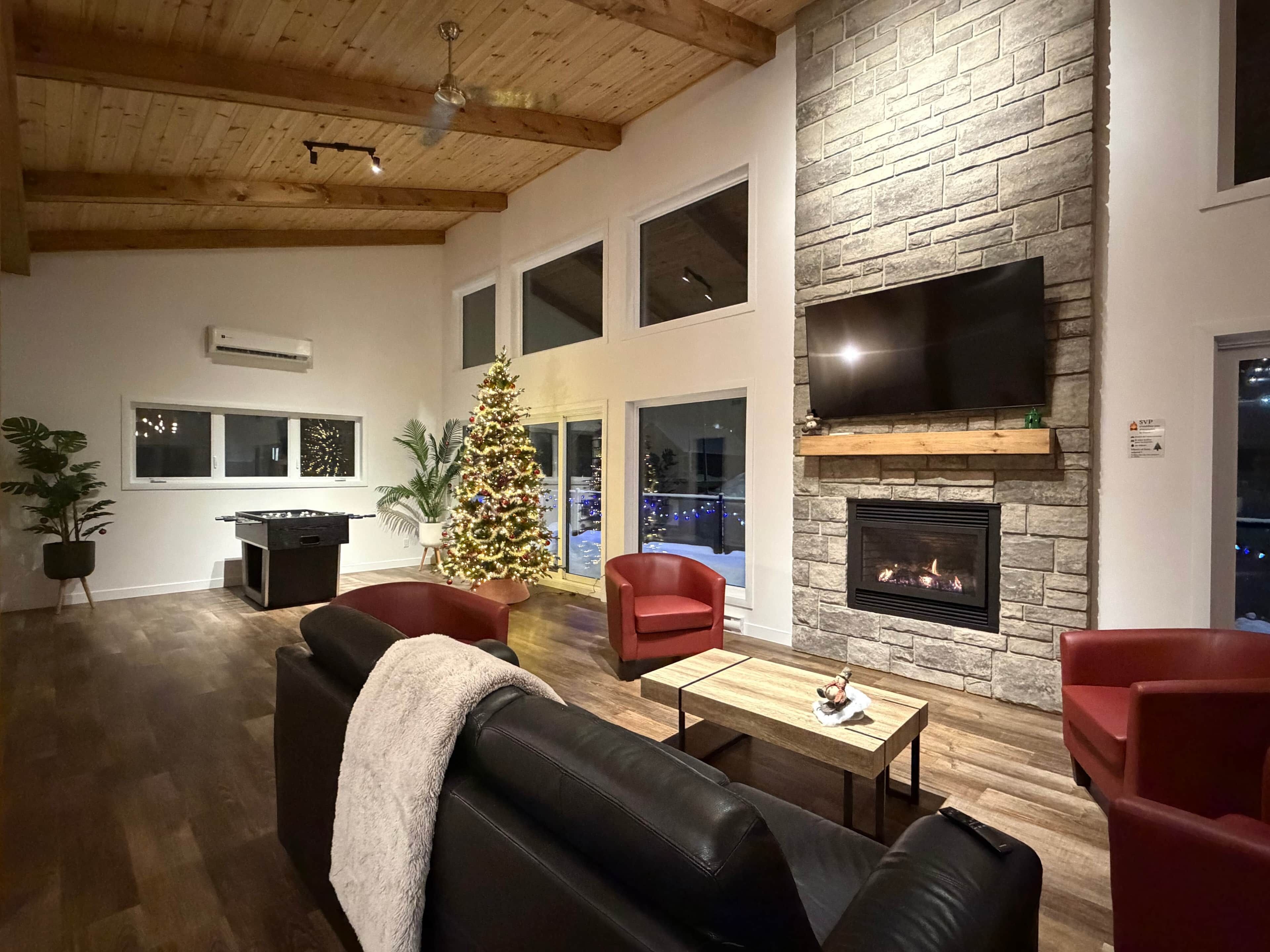 A modern living room with a fireplace, a Christmas tree, and a cozy seating area.
