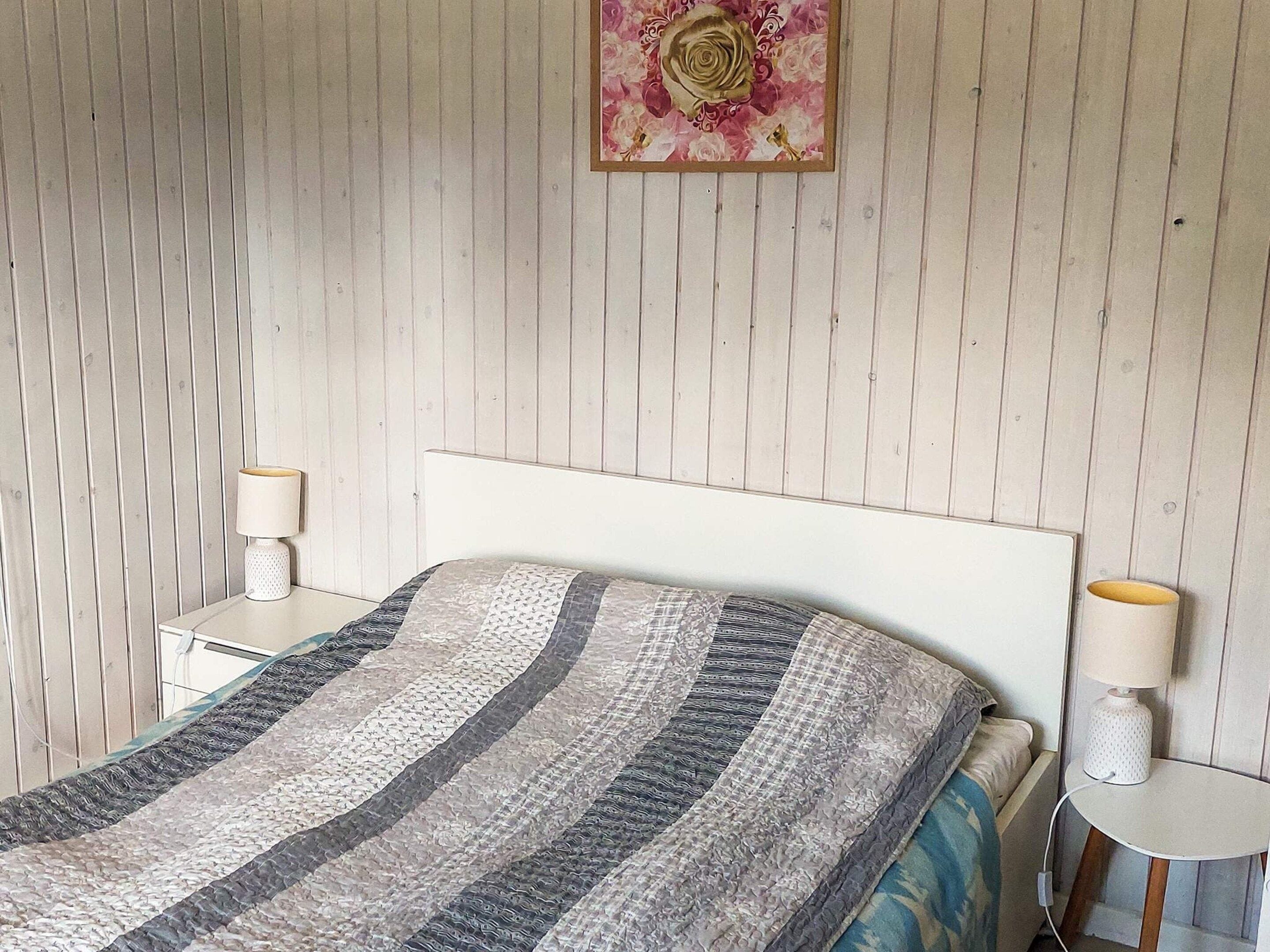 Een slaapkamer met een bed, twee nachtkastjes en een aan de muur hangend schilderij.