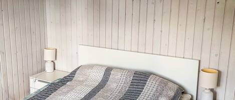 Een slaapkamer met een bed, twee nachtkastjes en een aan de muur hangend schilderij.
