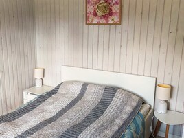 Un dormitorio con cama, dos mesitas de noche y un cuadro colgado en la pared.