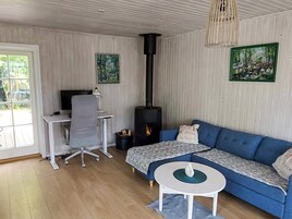 Una sala de estar acogedora con un sofá azul, una pequeña mesa redonda, una chimenea y un escritorio con una silla.