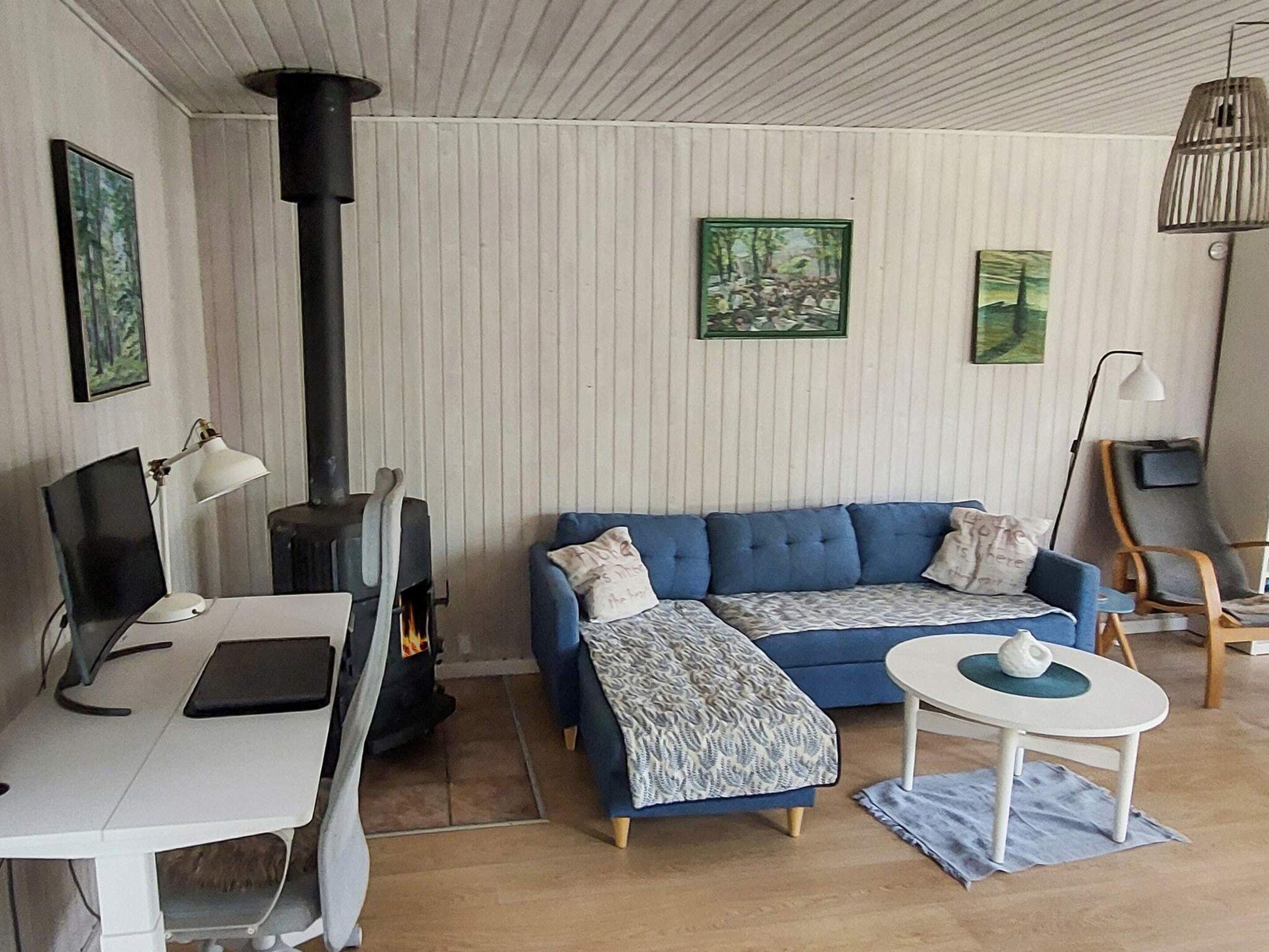 Un salon chaleureux avec un canapé bleu, une table blanche, une cheminée et des œuvres d’art accrochées aux murs.
