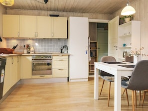 Eine kompakte Küche mit Holzboden, einem weißen Esstisch und einem eingebauten Backofen.