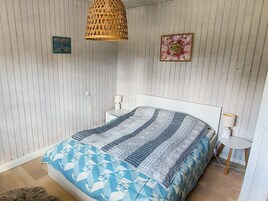 Un dormitorio con cama, mesita de noche, lámpara, lámpara colgante y un cuadro en la pared.