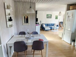 Una cocina moderna con muebles blancos, una mesa de comedor con sillas y un sofá azul al fondo.