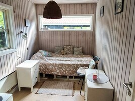 Un dormitorio con cama, escritorio, silla, ventana y lámpara colgante.