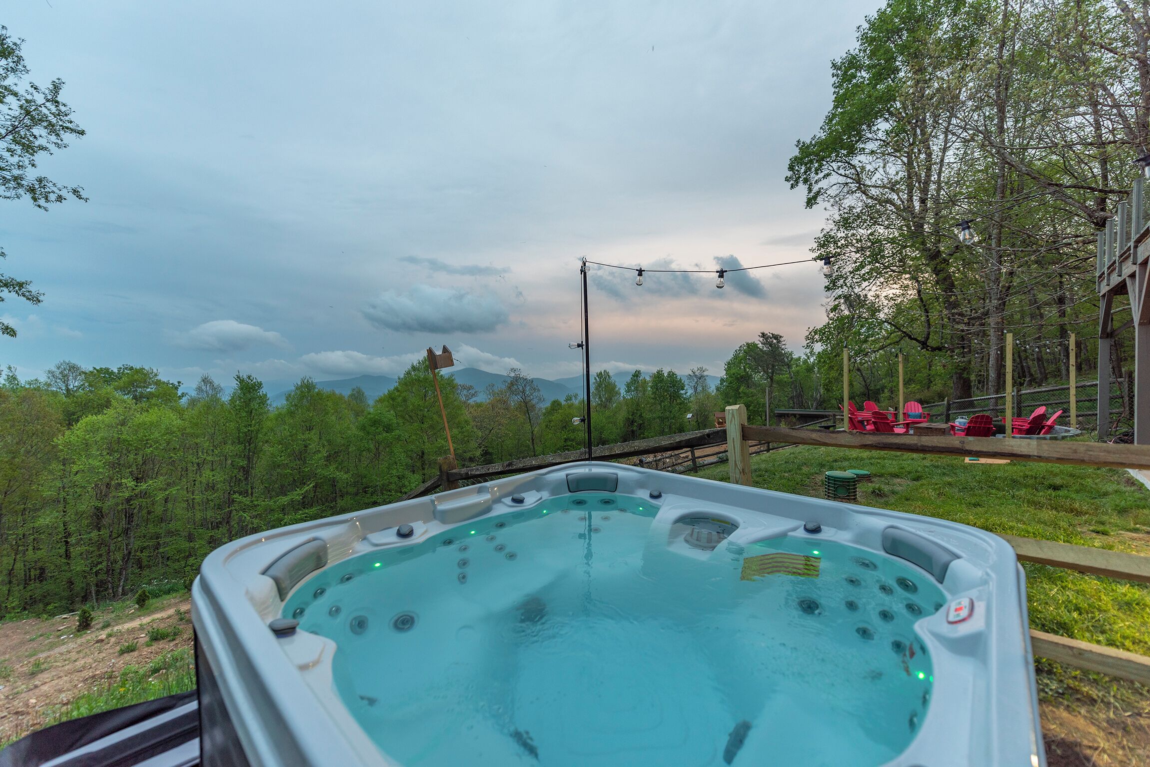 A hot tub with a view of a forest and mountains in the background.