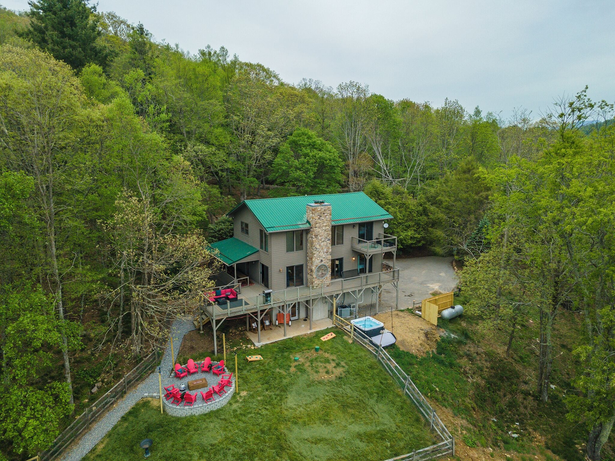 A two-story house with a stone chimney, a deck, and a swimming pool.