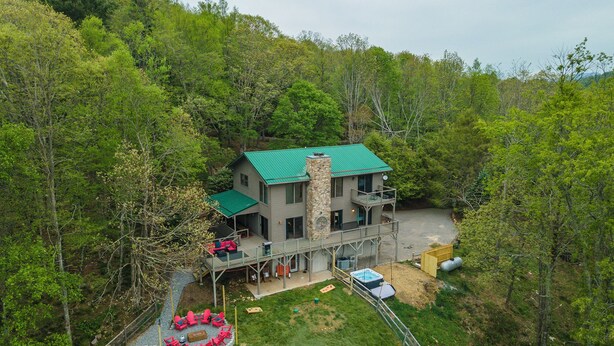 Ein zweistöckiges Haus mit einem Steinsschornstein, einer Terrasse und einem Swimmingpool.