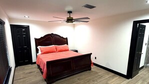 Un dormitorio con una cama, un ventilador de techo y una puerta.