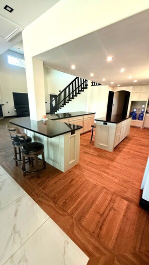 A spacious kitchen with a central island, a dining area with chairs, and a staircase leading to another level. - Hacienda Bonita (Del Rio)