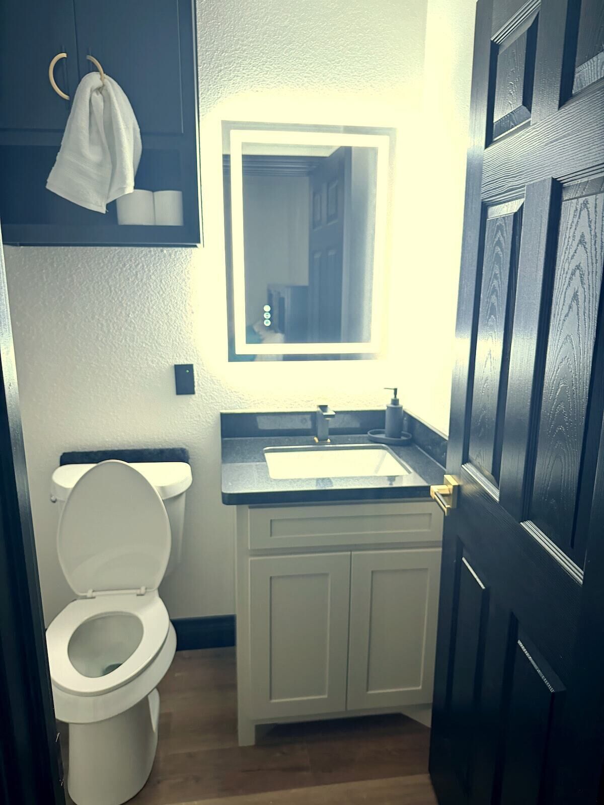 A bathroom with a toilet, sink, and mirror.