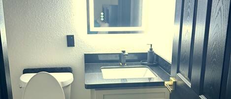 A bathroom with a toilet, sink, and mirror.