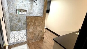 Un baño moderno con ducha, tocador y espejo.