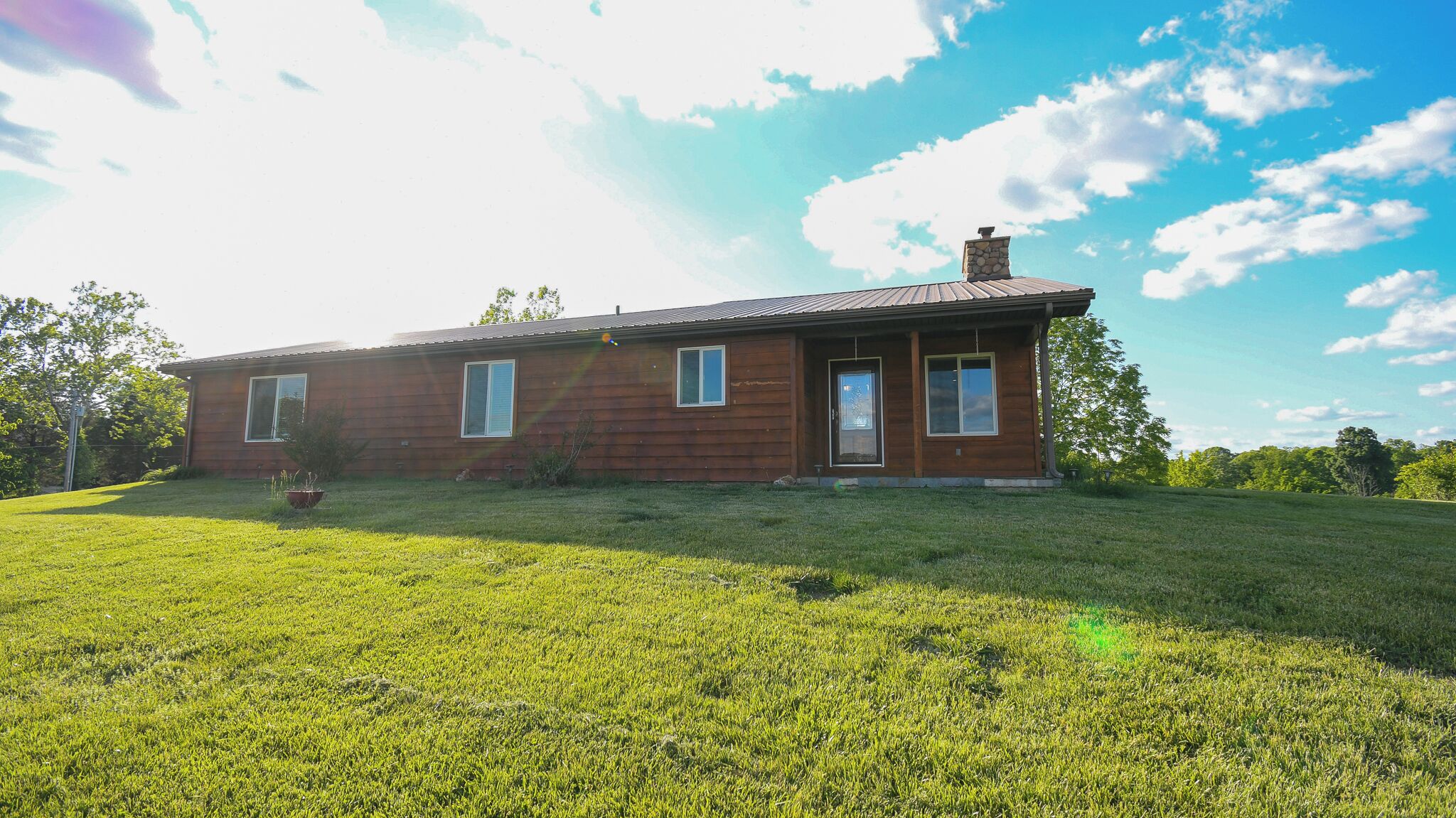 A single-story wooden house with a sloped roof, a front porch, and a well-maintained lawn.
