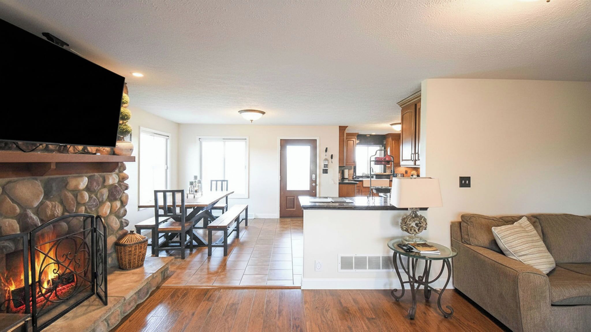 A living room with a fireplace, a dining area, and a kitchen in the background.