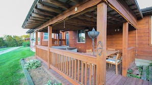 Une terrasse en bois avec des sièges d’extérieur, un luminaire suspendu et une vue sur le paysage environnant.