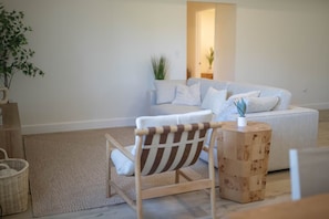 A modern living room with a sofa, a striped chair, a wooden side table, and a plant.