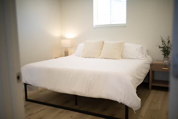 A bedroom with a bed, a nightstand, a lamp, and a window. - 3-bedroom house in nice Clovis with cool AC for relaxing stays (Clovis)