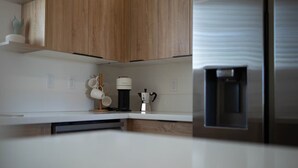 Une cuisine moderne avec des meubles en bois, une machine à café et un distributeur d’eau.