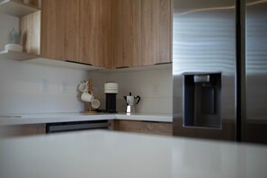 A modern kitchen with wooden cabinets, a coffee machine, and a water dispenser.
