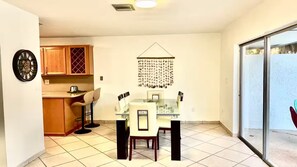 A dining area with a glass table, chairs, and a wall-mounted decorative item.
