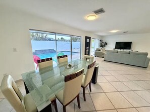A spacious living area with a dining table, chairs, a sofa, and a TV.