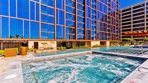 Um edifício moderno com fachada de vidro extensa e área de piscina com banheiras de hidromassagem.