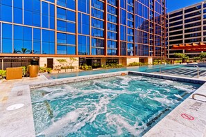 Een modern gebouw met een grote glazen gevel en een zwembad met whirlpools.