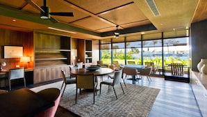 Um interior moderno com área de refeições, cozinha e grandes janelas que oferecem vista para o exterior.