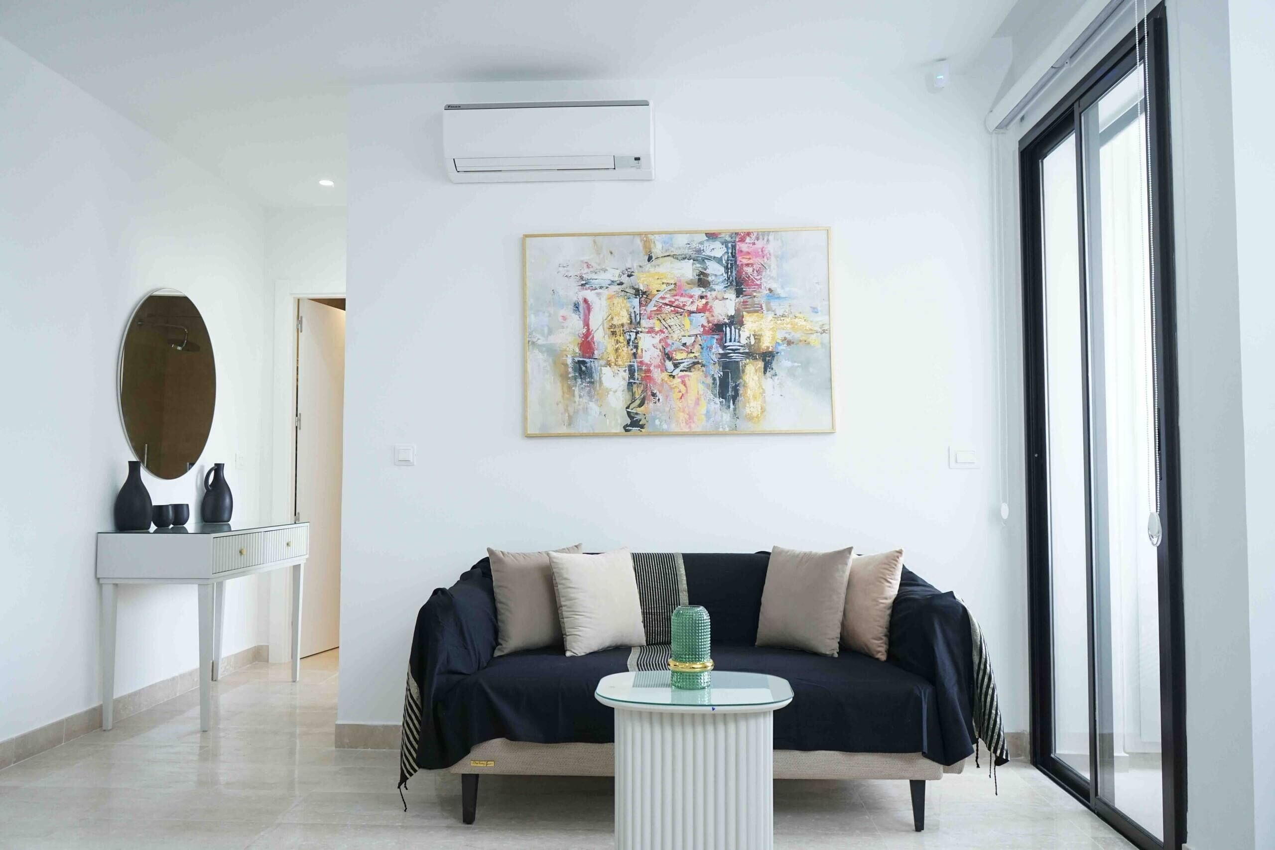 A modern living room with a sofa, a coffee table, and a large abstract painting on the wall.