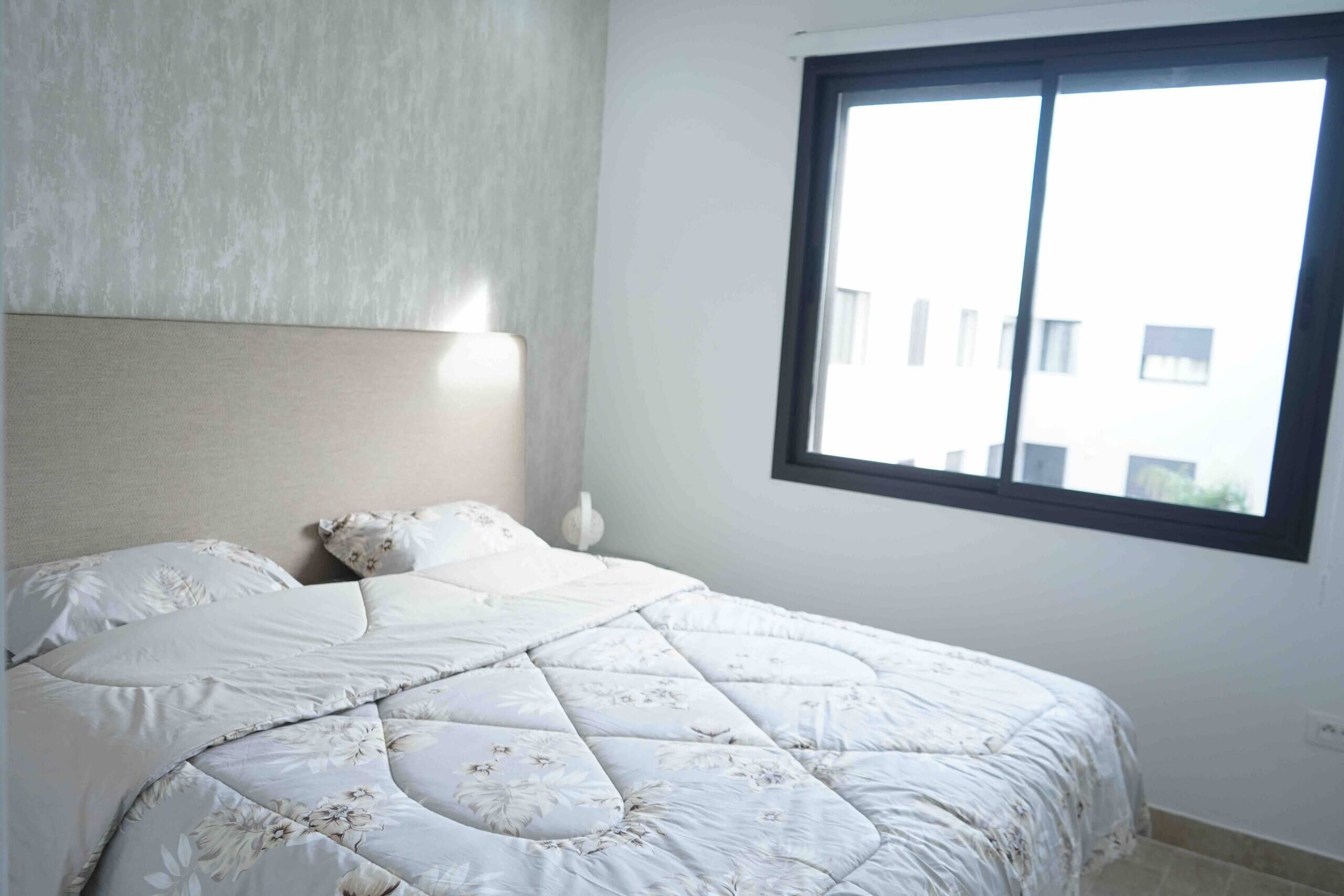 Ein Schlafzimmer mit einem Bett, einem Nachttisch und einem Fenster.