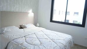 A bedroom with a bed, a nightstand, and a window.