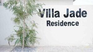 A sign for Villa Jade Residence with a tree in front.