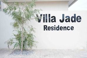 A sign for Villa Jade Residence with a tree in front.