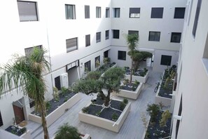 Une cour intérieure à plusieurs niveaux, dotée de nombreux balcons, de plantes en pot et d’un vélo.