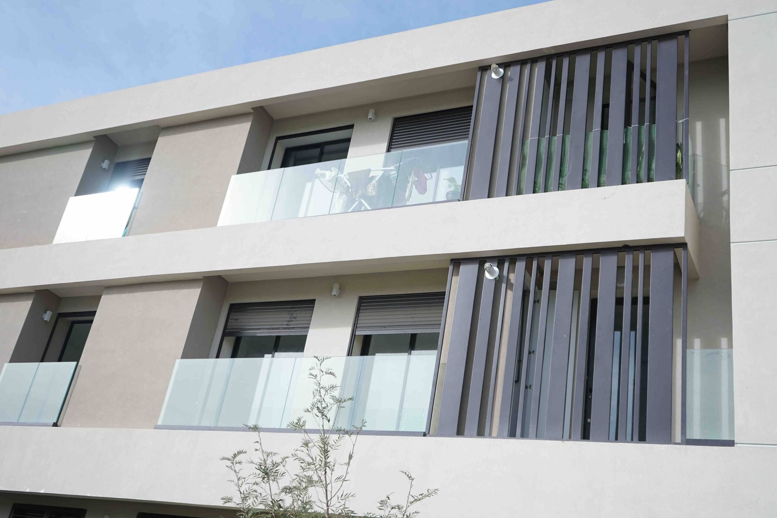 A multi-story building with balconies, large windows, and a flat facade.