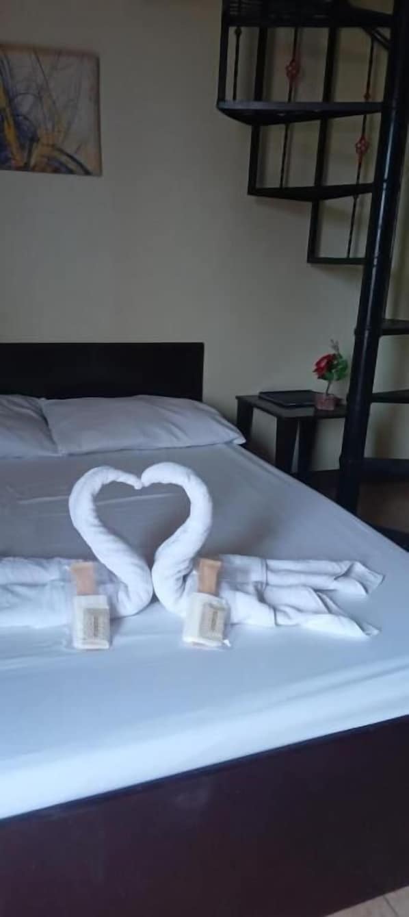 A bed with a heart-shaped towel arrangement and two bottles of lotion. - Central View Apartelle (Angeles)