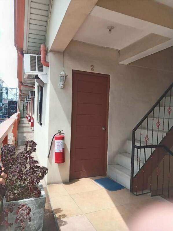 A hallway with a fire extinguisher, a door, and a staircase.