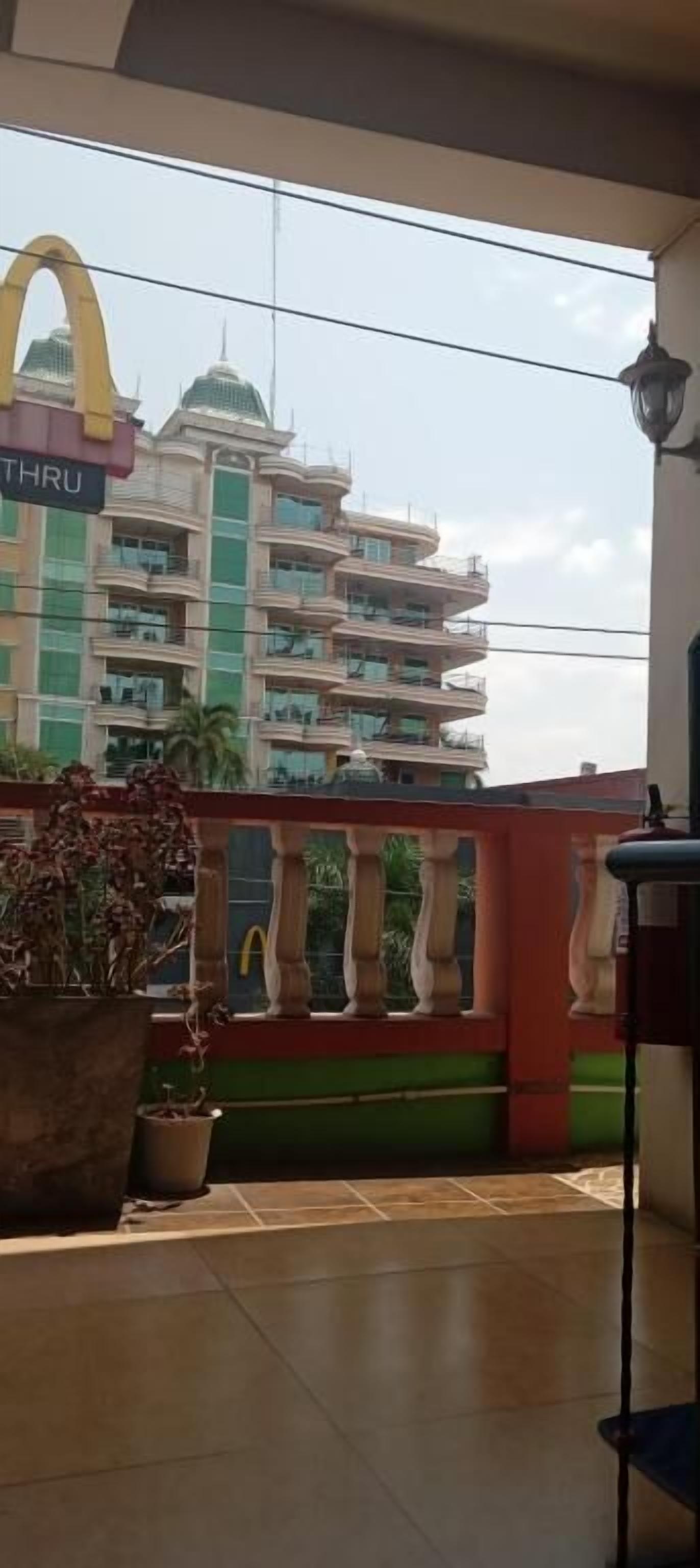 Un balcón con vista a un edificio de varios pisos con el logotipo de McDonald's, una planta en maceta y una barandilla.