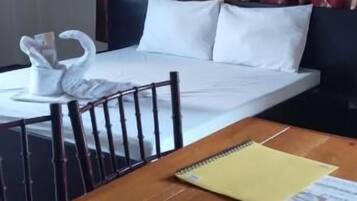 A hotel room with a bed, a wooden table with a notebook, and a swan-shaped object on the table.