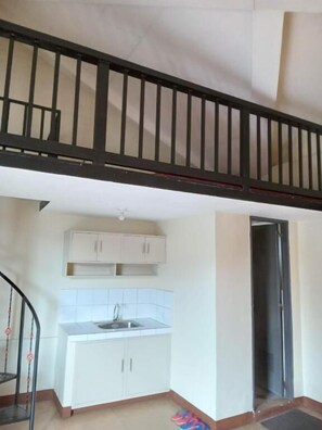A kitchen with white cabinets, a sink, and a black railing above. - Central View Apartelle (Angeles)