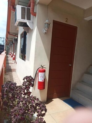 A building entrance with a fire extinguisher, a door, and a staircase.