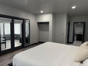 A modern hotel room with a large bed, a seating area with a sofa and chairs, a small table, and a sliding glass door leading to a balcony. - Beautiful Rustic 4-bedroom farm house with AC in charming Clovis (Clovis)