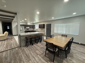 A modern kitchen with a central island, a dining area with a wooden table and chairs, and a hallway leading to another room. - Beautiful Rustic 4-bedroom farm house with AC in charming Clovis (Clovis)