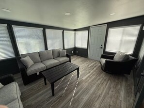 A room with a grey sofa, a black coffee table, and a wicker chair.